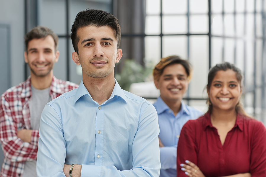 Proud professional group standing in office with their arms crossed.