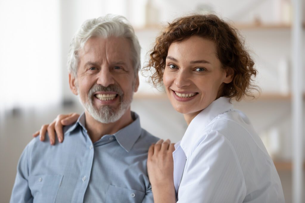 Portrait of smiling female nurse supporting mature patient.